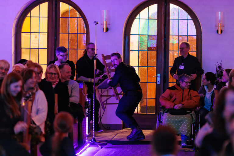 Schlagzeuger wird auf einem Stuhl durch die Kirche getragen